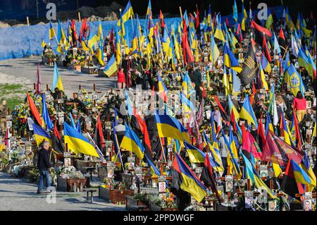 Lemberg, Ukraine. 23. April 2023. Die Menschen sahen inmitten von Flaggen, wie sie ihren Respekt auf den Gräbern der Angehörigen auf dem Marsfeld des Friedhofs Lychakiv zollten. Die Menschen besuchen die gefallenen Helden der Ukraine, die das Territorium der Ukraine auf dem Friedhof Lychakiv verteidigten, wo sie begraben sind. Russland marschierte am 24. Februar 2022 in die Ukraine ein und löste damit den größten militärischen Angriff in Europa seit dem Zweiten Weltkrieg aus Kredit: SOPA Images Limited/Alamy Live News Stockfoto