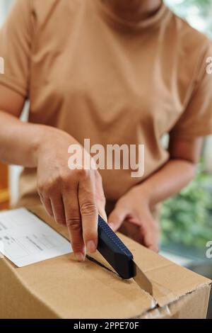 Eine Frau mit einem scharfen Papiermesser, die auspackt Stockfoto