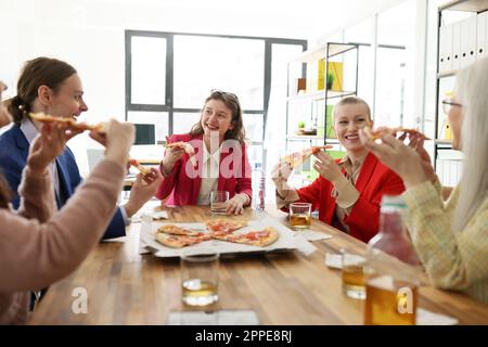 Zufriedene Mitarbeiter des Unternehmens genießen Fastfood auf einer Pizzaparty im Büro Stockfoto