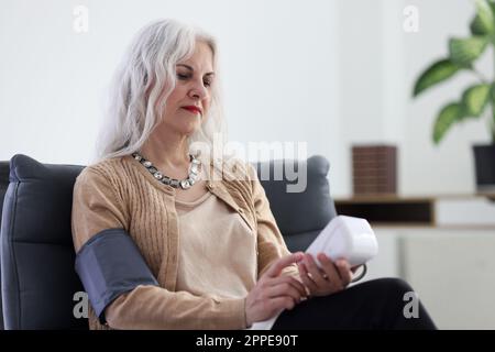 Alte Frau verwendet ein digitales Tonometer zur Blutdruckmessung Stockfoto