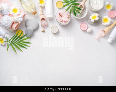 Beauty- und Spa-Konzept auf weißem Betonhintergrund. Blauer Lehm mit Creme und Massagesteinen. Massagekonzept. Massageöl mit Franjipani-Blumen. Stockfoto