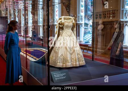 Das Dossierfoto des Kronkleides der Königin Elizabeth II. Vom 06. Dezember 07/22 ist im Platinum Jubilee: The Queen's Krönung ausgestellt, einer Sonderausstellung in der St George's Hall und in der Lantern Lobby von Windsor Castle, Berkshire. Königin Elizabeth II. Bestand darauf, dass ihr historisches Krönungskleid aus dem Jahr 1953 Länder aus der ganzen Welt repräsentieren sollte, über die sie herrschte. Das reich bestickte Satinkleid des britischen Couturiers Sir Norman Hartnell gilt als eines der wichtigsten Beispiele für das Design des 20. Jahrhunderts. Ausgabedatum: Montag, 24. April 2023. Stockfoto