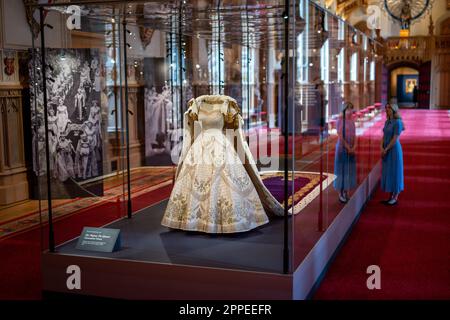 Das Dossierfoto des Kronkleides der Königin Elizabeth II. Vom 06. Dezember 07/22 ist im Platinum Jubilee: The Queen's Krönung ausgestellt, einer Sonderausstellung in der St George's Hall und in der Lantern Lobby von Windsor Castle, Berkshire. Königin Elizabeth II. Bestand darauf, dass ihr historisches Krönungskleid aus dem Jahr 1953 Länder aus der ganzen Welt repräsentieren sollte, über die sie herrschte. Das reich bestickte Satinkleid des britischen Couturiers Sir Norman Hartnell gilt als eines der wichtigsten Beispiele für das Design des 20. Jahrhunderts. Ausgabedatum: Montag, 24. April 2023. Stockfoto