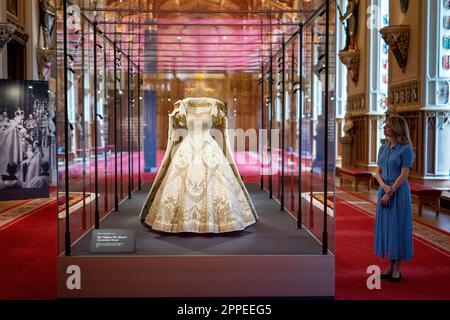 Das Dossierfoto des Kronkleides der Königin Elizabeth II. Vom 06. Dezember 07/22 ist im Platinum Jubilee: The Queen's Krönung ausgestellt, einer Sonderausstellung in der St George's Hall und in der Lantern Lobby von Windsor Castle, Berkshire. Königin Elizabeth II. Bestand darauf, dass ihr historisches Krönungskleid aus dem Jahr 1953 Länder aus der ganzen Welt repräsentieren sollte, über die sie herrschte. Das reich bestickte Satinkleid des britischen Couturiers Sir Norman Hartnell gilt als eines der wichtigsten Beispiele für das Design des 20. Jahrhunderts. Ausgabedatum: Montag, 24. April 2023. Stockfoto