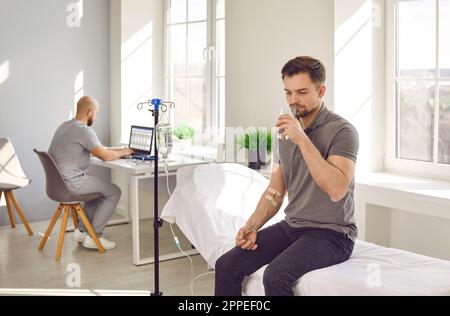 Mann in der Praxis in der Klinik unter intravenöser Tropfinfusion und Vitamintherapie Stockfoto