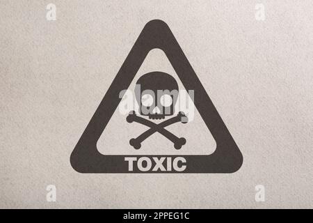 Warnschild (Schädel- und Querlenkersymbol und Wort „GIFTIG“) auf Papier, Draufsicht Stockfoto