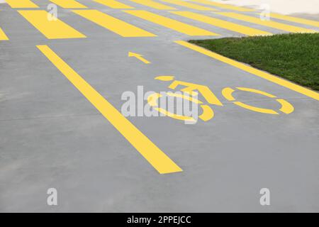 Fahrradweg mit gemaltem gelbem Fahrradschild und Pfeil in der Nähe des Fußgängerübergangs Stockfoto