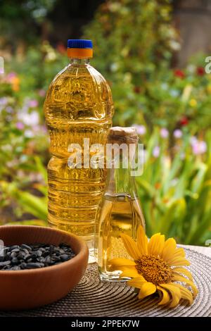 Flaschen mit Sonnenblumenöl und Samen in der Schüssel auf dem Tisch im Freien Stockfoto