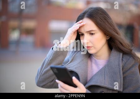 Besorgte Frau, die im Winter auf der Straße ihre Nachricht abhört Stockfoto