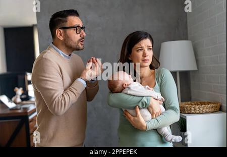 Junger Vater mit Baby und Frau, die zu Hause an postnataler Depression leidet Stockfoto