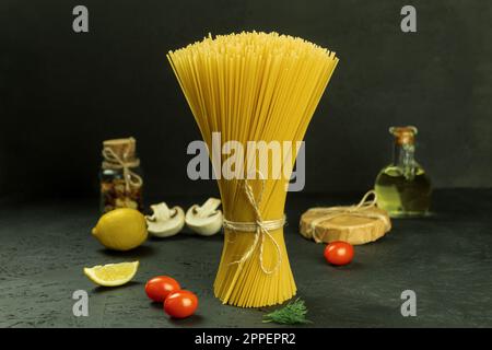 Eine Auswahl an Pasta und Spaghetti auf dunklem Hintergrund. Rohe Pasta zum Kochen italienischer Küche auf einem Holztisch auf dunklem Hintergrund. Speicherplatz kopieren Stockfoto