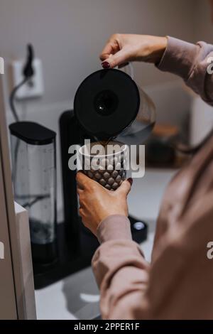 Frauenhände schütten Kaffee in eine Tasse Stockfoto