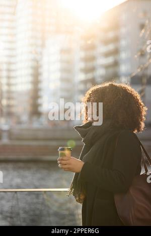 Schöne Frau mit Kaffee zum Mitnehmen, die in der Stadt spaziert Stockfoto