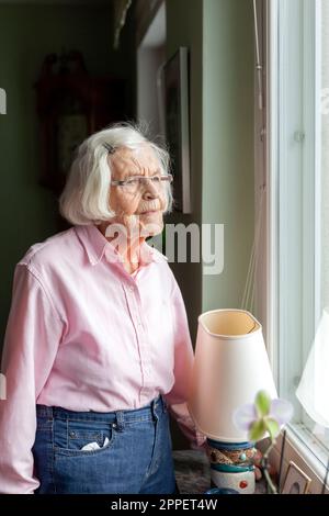 Ältere Frau, die durch Fenster Stockfoto