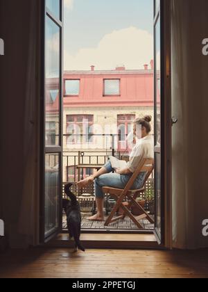 Frau liest Buch auf dem Balkon Stockfoto
