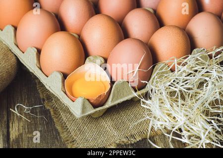 Frisch gepflückte Hühnereier auf rustikalem Hintergrund. Hühnereier in Heu, ländliche Szene Stockfoto