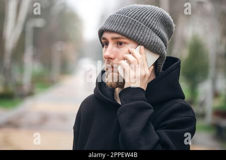 Ein junger Mann mit Bart telefoniert. Stockfoto