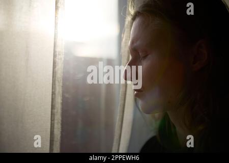 Blick auf eine Frau, die vor dem Fenster steht Stockfoto