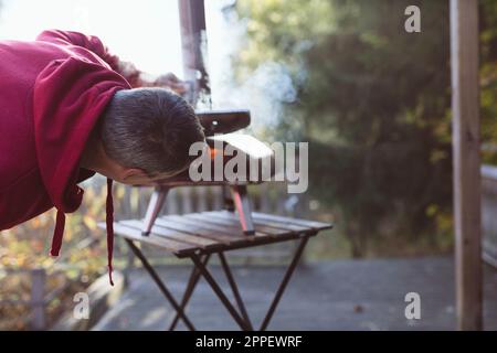 Ein Mann, der Feuer im Pizzaofen im Freien legt Stockfoto