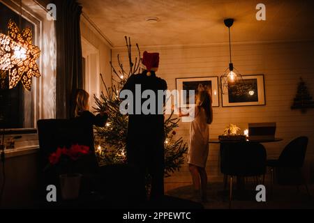 Vater und Töchter schmücken den Weihnachtsbaum Stockfoto
