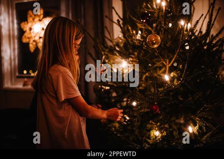 Mädchen schmücken Weihnachtsbaum zu Hause Stockfoto