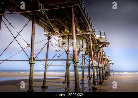 Salzbrand-am-Meer. Am Strand mit Blick auf die Unterseite des alten viktorianischen Piers. Stockfoto