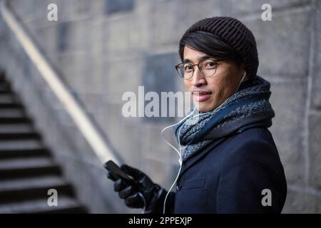 Attraktiver Mann mit Smartphone auf der Straße Stockfoto