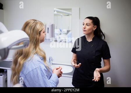 Zahnärztin spricht mit Patientin in der Praxis Stockfoto
