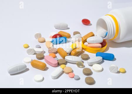 Viele Pillen auf dem Tisch, Nahaufnahme. Tabletten mit unterschiedlichen Formen und Farben sind auf dem Tisch verstreut. Die Pillen sind aus der Flasche gelaufen Stockfoto