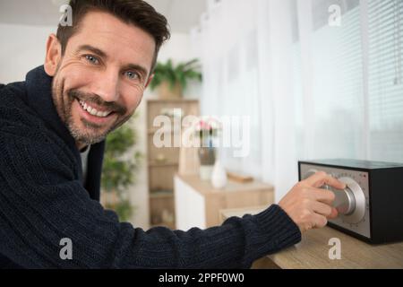 Mann, der das Wahlrad auf das Audiogerät stellt Stockfoto