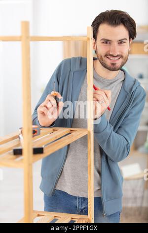 Der junge Mann versucht, ein neues Regal zu bauen Stockfoto