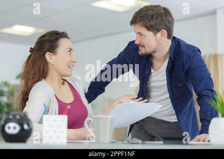 Ein Paar, das sich zu Hause in der Küche mit Laptop-Papieren unterhält Stockfoto