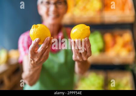Ein Arbeiter im Obst- und Gemüseladen hält Zitronen. Nahaufnahme von Zitrone. Stockfoto