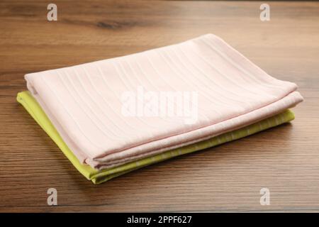 Pinkfarbene und gelbe Küchentücher auf Holztisch Stockfoto