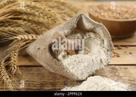 Mehlsack mit Holzschaufel und Weizenohren auf einem Holztisch Stockfoto