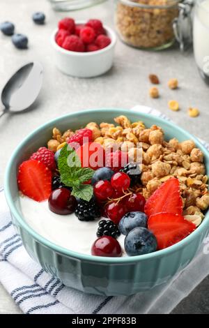 Schüssel mit leckerem Müsli und Beeren auf einem hellgrauen Tisch. Gesundes Essen Stockfoto