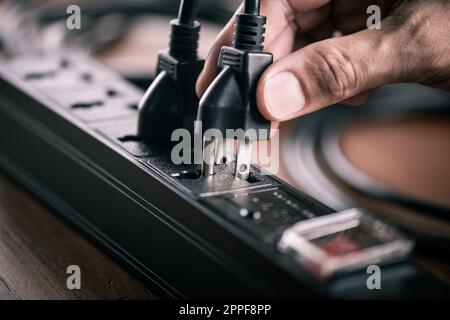 Nahaufnahme einer hand, die einen Stecker in die Steckdosenleiste steckt. Stockfoto