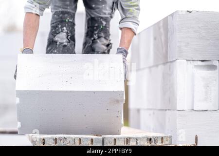 Ein Mauerwerk baut die Wand eines Hauses aus Betonziegeln Stockfoto