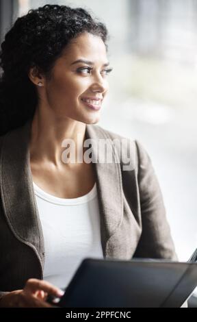 Sie bereitet sich immer auf den Erfolg vor. Eine junge Geschäftsfrau, die in einem Büro eine Geschäftsmappe liest. Stockfoto