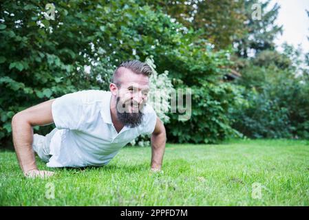 Junger Mann, der Liegestütze im Garten macht, Bayern, Deutschland Stockfoto