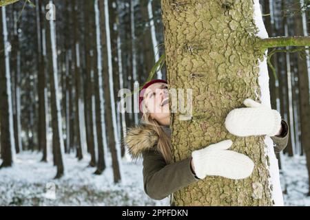 Teenager, die einen Baum in einem Wald umarmt, Bayern, Deutschland Stockfoto