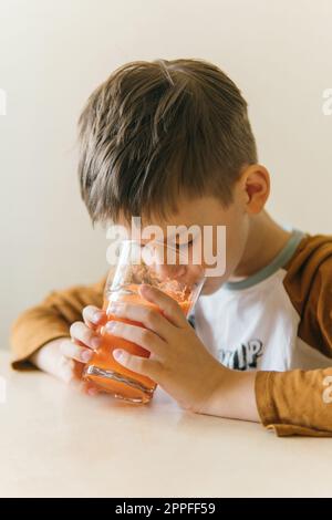 Ein Weißer trinkt morgens Orangensaft am Tisch Stockfoto