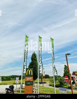 Kiel, Deutschland - 1. Juli 2022: Flaggen der Fast-Food-Kette MC Donalds vor einem Restaurant. Stockfoto