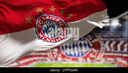 Die Bayern Münchner Flagge winkt im Wind mit dem Allianza Arena Stadion verschwommen im Hintergrund Stockfoto