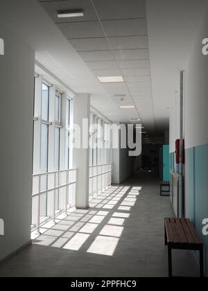 Sremska Mitrovica, Serbien, 15. Mai 2021. Schulkorridor in einer neuen modernen Schule. Weißes Interieur des Foyers. Hohe Decken, große weiße Plastikfenster. Die Sonnenstrahlen fallen in den Raum Stockfoto