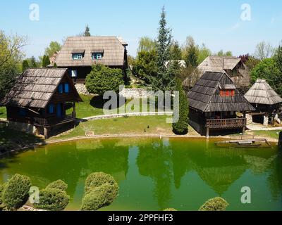 Stanisici, Bijelina, Bosnien und Herzegowina. 25. April 2021 Ethno-Dorf, traditionelle Dorfhäuser aus Baumstämmen, bosnischer Baustil im Hochland. See mit Wasser. Holzarchitektur. Stockfoto