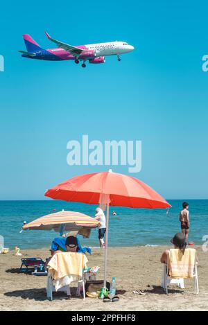 Larnaca, Zypern - 17. September 2022: Menschen, die sich am Strand von Mackenzie ausruhen und Airbus A320-232 der Wizz Air-Fluggesellschaft landen Stockfoto