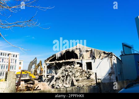 Abriss des alten Gebäudes mit Sloopkraan gegen den blauen Wolkenhimmel. Stockfoto