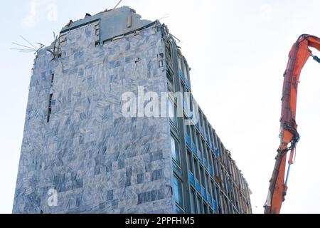 Abriss des alten Gebäudes mit Sloopkraan gegen den blauen Wolkenhimmel. Stockfoto