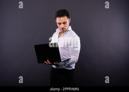 Fröhlicher junger Mann 20s in klassischem Hemd isoliert auf dunklem Studioporträt im Hintergrund. Stockfoto